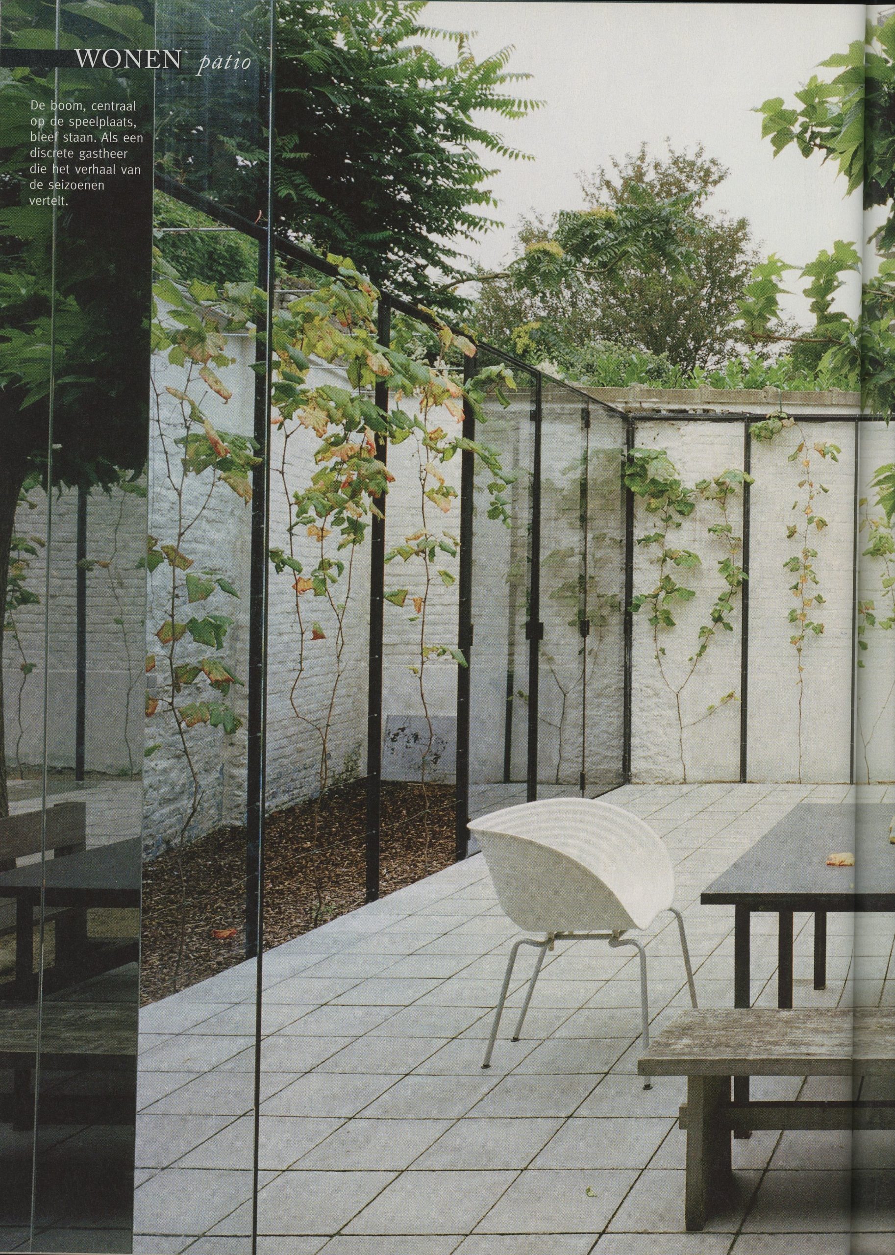 Magazine-publicatie met patio achter glazen wand en design-stoel